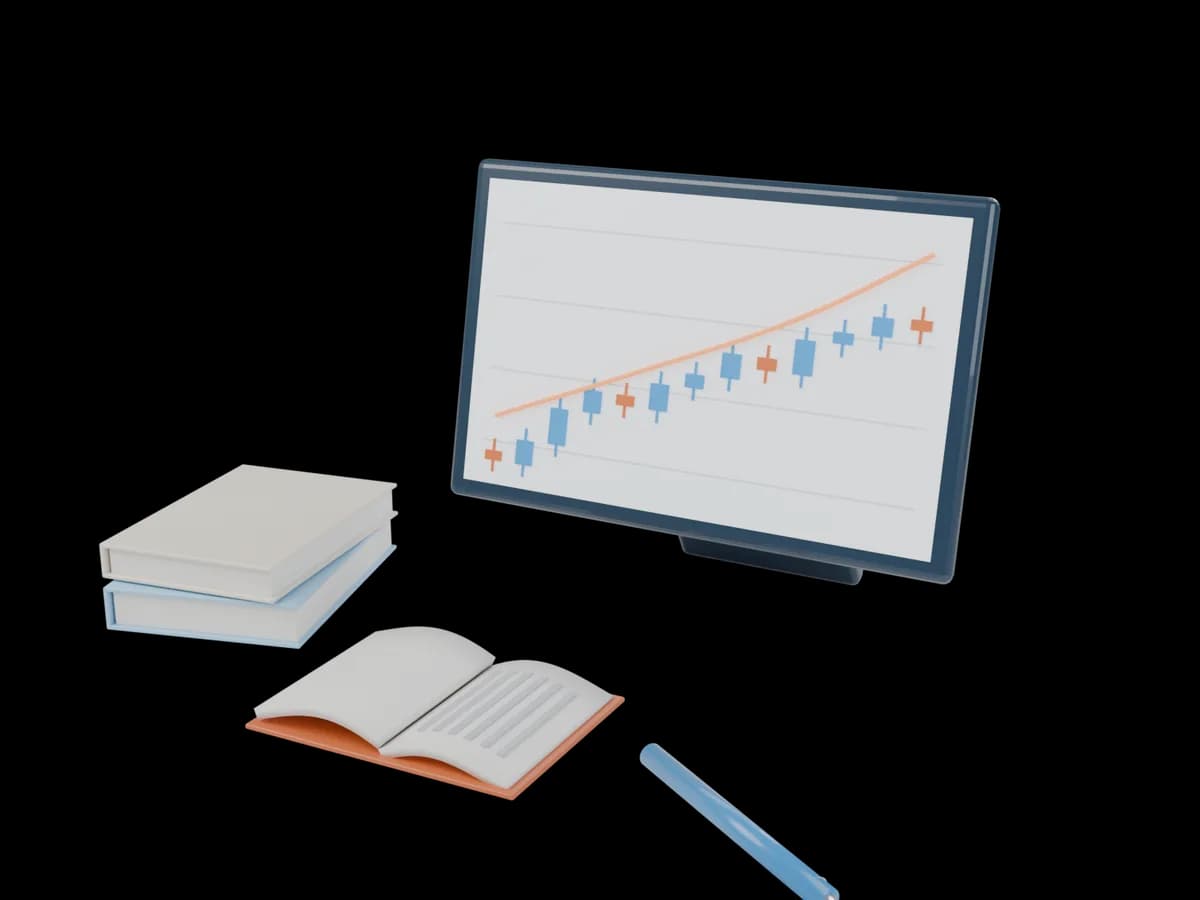 A screen with a rising stock chart beside an open book and a pen
